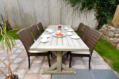 Gemütlich gedeckter Gartentisch mit Stühlen auf einer sonnigen Terrasse einer Ferienwohnung auf Sylt