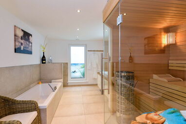 Modernes Badezimmer mit freistehender Badewanne und integrierter Holzsauna in einer stilvollen Ferienwohnung auf Sylt